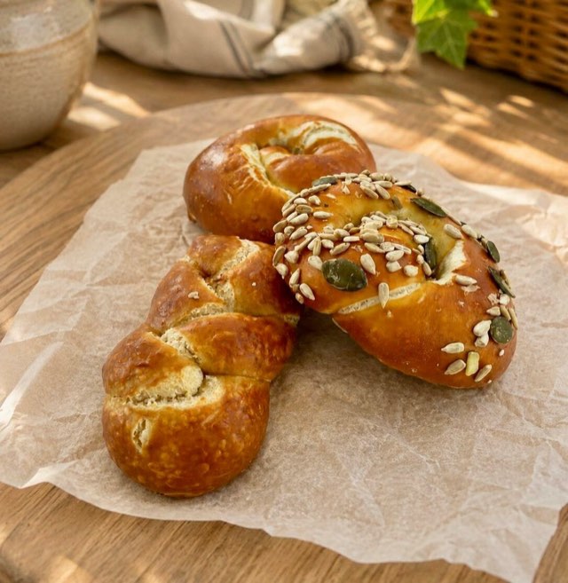 Geflochtene Laugenbrötchen mit Kernen auf Backpapier